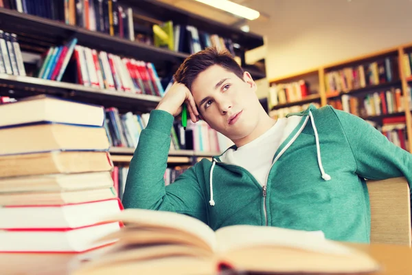 Скучающий студент или молодой человек с книгами в библиотеке — стоковое фото