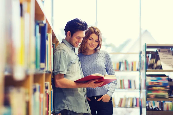 Lycklig student par med böcker i biblioteket — Stockfoto