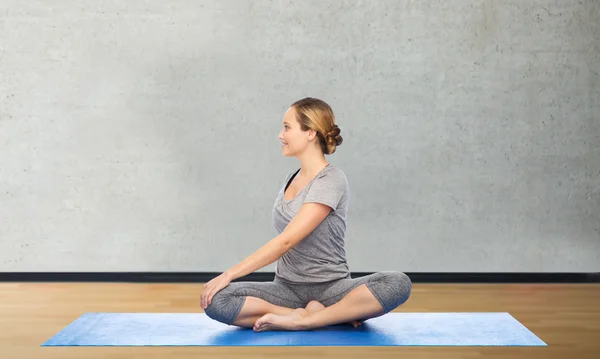 Donna che fa yoga in posa torsione sul tappeto — Foto Stock