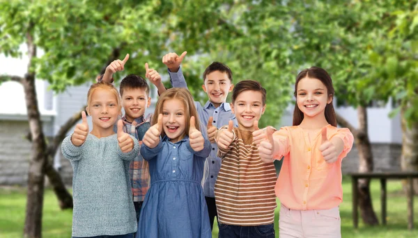 Happy children showing thumbs up over backyard — Stockfoto