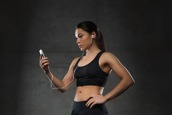 Woman with smartphone and earphones in gym — Stock Photo, Image
