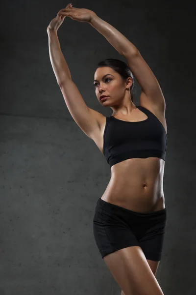 Jeune femme posant et montrant des muscles dans la salle de gym — Photo