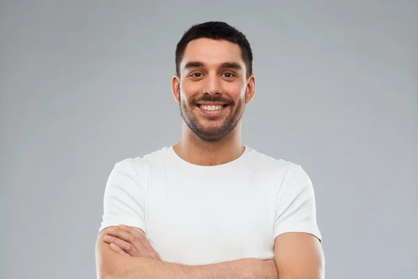 Uomo sorridente con le braccia incrociate su sfondo grigio — Foto Stock