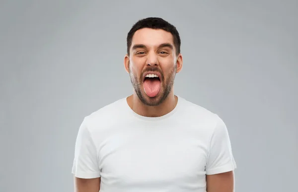 Man showing his tongue over gray background — Stock Photo, Image