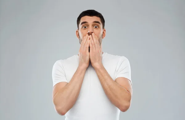 Scared man in white t-shirt over gray background — Stock Photo, Image