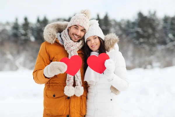 Lyckliga par med röda hjärtan över vinterlandskap — Stockfoto