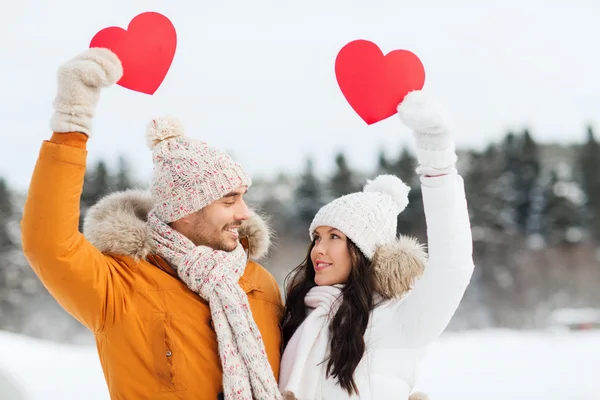 Casal feliz com corações vermelhos sobre paisagem de inverno — Fotografia de Stock