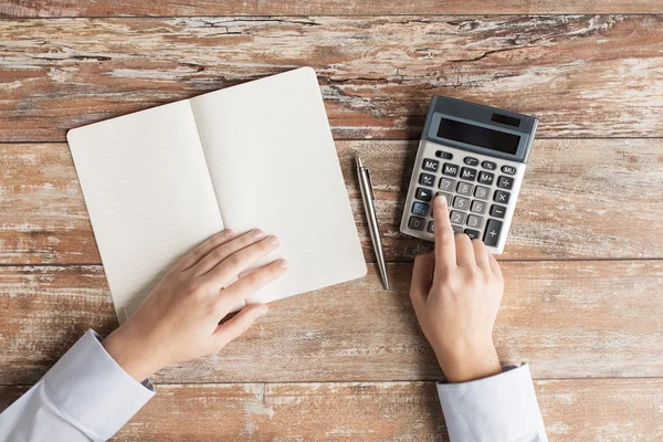 Close up of hands with calculator and notebook — Stock Photo, Image