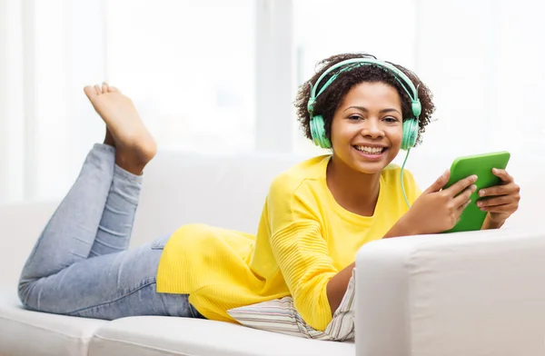 Mujer africana feliz con la PC tableta y auriculares —  Fotos de Stock