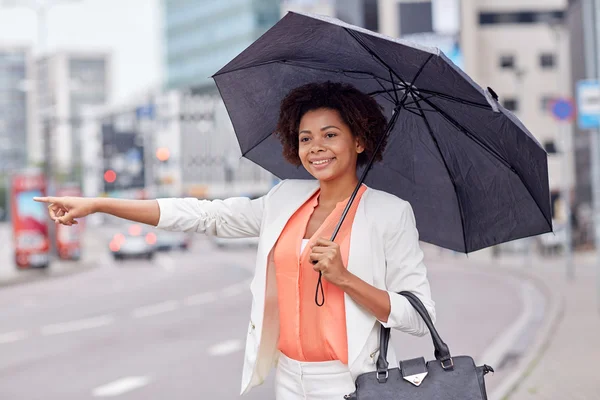 Happy african woman with umbrella catching taxi — Φωτογραφία Αρχείου