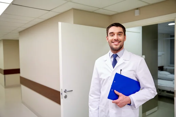 Happy doctor with clipboard at hospital corridor — Stock Photo, Image