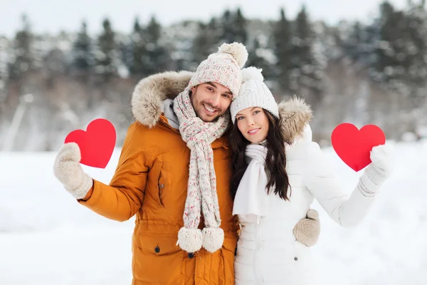 Feliz pareja con corazones rojos sobre el paisaje de invierno —  Fotos de Stock