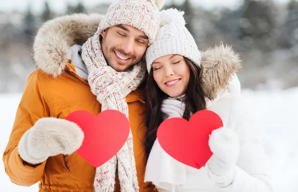 Šťastný pár s červenými srdci nad zimní krajina — Stock fotografie