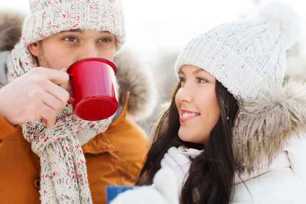 Happy couple with tea cups over winter landscape — Stock Photo, Image
