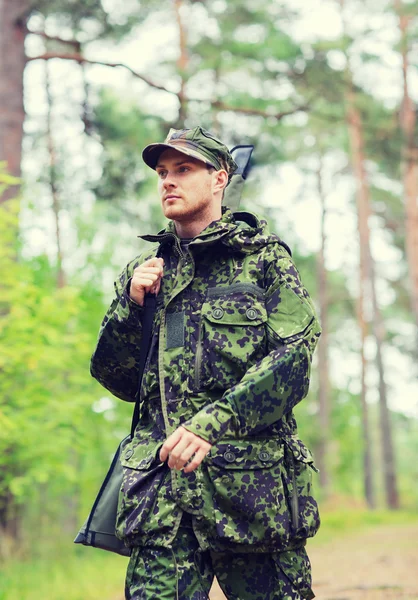 Jovem soldado ou caçador com arma na floresta — Fotografia de Stock