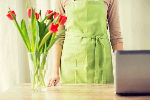 Primo piano di donna con tulipani in vaso e computer portatile — Foto Stock