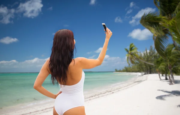 Mujer joven tomando selfie con smartphone en la playa — Foto de Stock