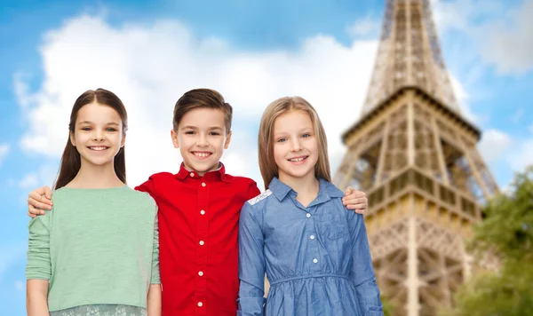 Happy boy and girls hugging over eiffel tower — Stock Photo, Image
