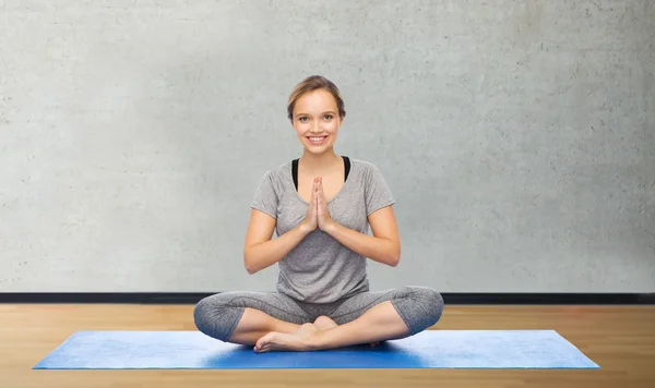 Vrouw maken van yoga meditatie in lotus pose op de mat — Stockfoto