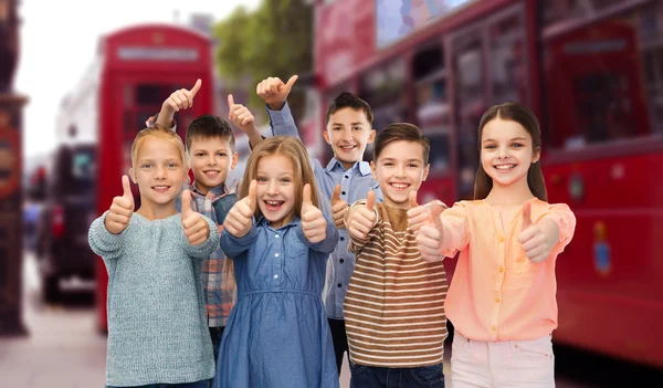 Niños felices mostrando pulgares hacia arriba sobre la ciudad de Londres — Foto de Stock