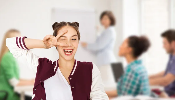 Happy teenage girl showing peace sign at school — Stock Photo, Image