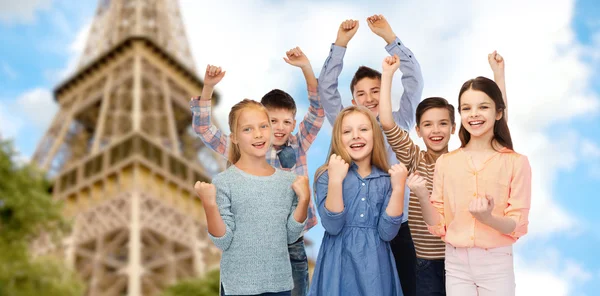 Happy kids celebrating victory over eiffel tower — Zdjęcie stockowe