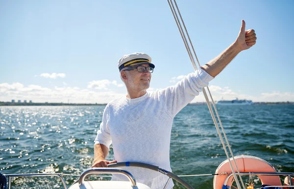 Homem sênior no leme em barco ou iate navegando no mar — Fotografia de Stock