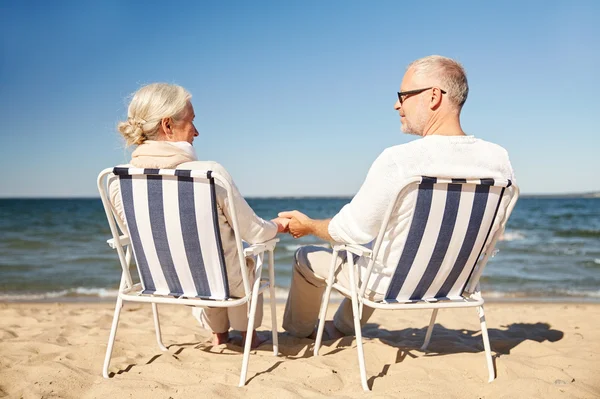 Щаслива старша пара в стільцях на літньому пляжі — стокове фото