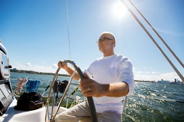 Hombre mayor al timón en barco o yate de vela en el mar —  Fotos de Stock