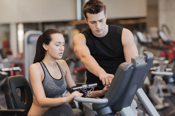 Mujer con entrenador en bicicleta estática en el gimnasio —  Fotos de Stock