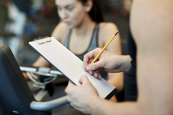 Nahaufnahme von Trainerhänden mit Klemmbrett im Fitnessstudio — Stockfoto