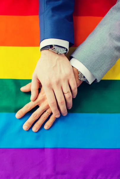 Close up of male gay couple hands on rainbow flag — Stock Photo, Image