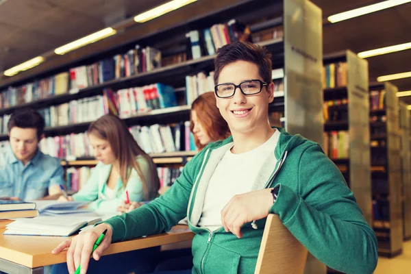 Gelukkig student jongen lezen van boeken in bibliotheek — Stockfoto