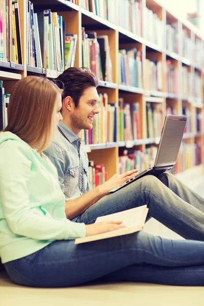 Studenti felici con laptop in biblioteca — Foto Stock