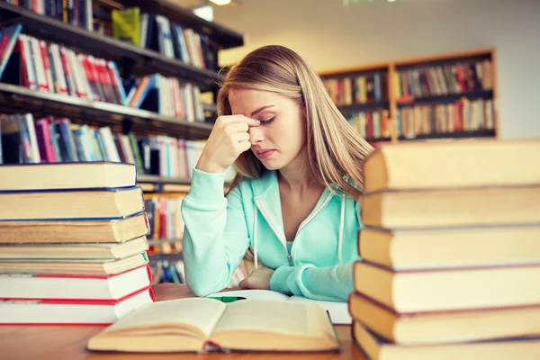 Verveeld student of jonge vrouw met boeken in bibliotheek — Stockfoto