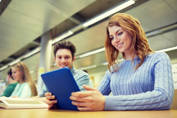 Estudiantes felices con tablet pc en la biblioteca —  Fotos de Stock