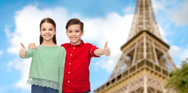 Menino e menina mostrando polegares para cima sobre eiffel torre — Fotografia de Stock