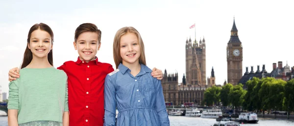 Happy boy and girls hugging over london — Stock fotografie