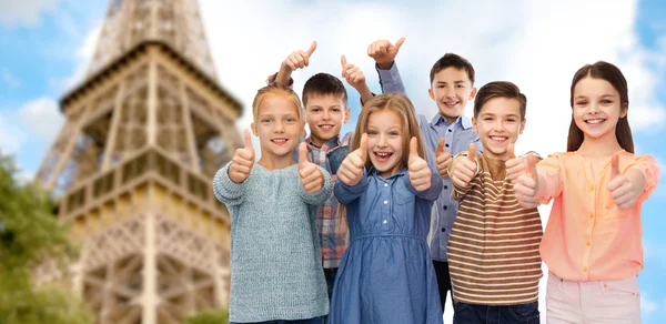 Happy children showing thumbs up over eiffel tower — Stock Photo, Image