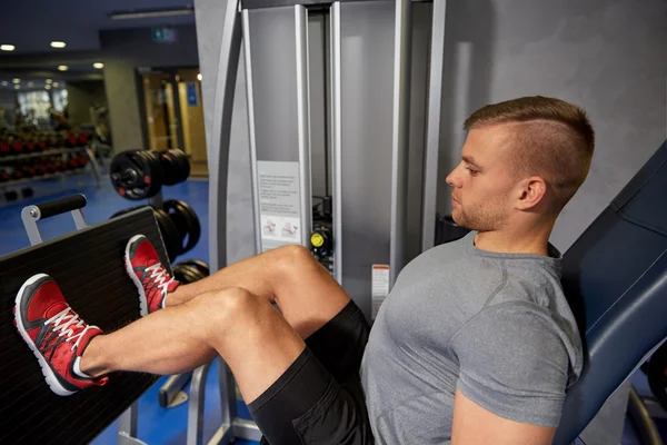 Man flexing leg muscles on gym machine — Stock Photo, Image