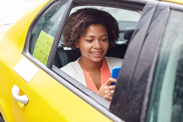 Glückliche Afrikanerin tickt im Taxi auf Smartphone — Stockfoto