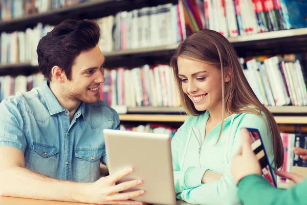 Happy students with tablet pc in library — Stock Photo, Image