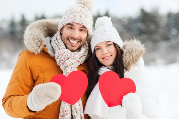 Feliz pareja con corazones rojos sobre el paisaje de invierno — Foto de Stock
