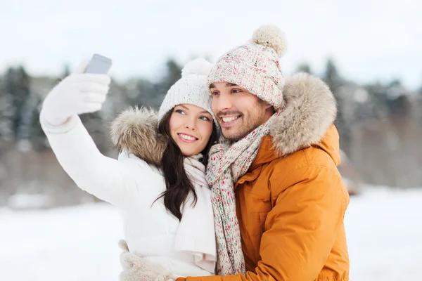 Счастливая пара делает селфи на смартфоне зимой — стоковое фото