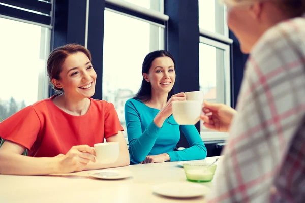 Glada unga kvinnor dricker te eller kaffe på café — Stockfoto