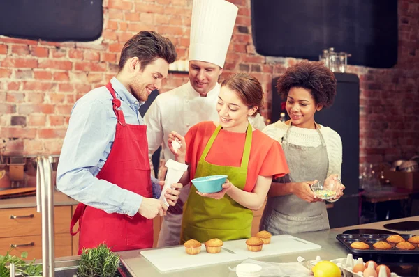 Happy friends and chef cook baking in kitchen — Stock Photo, Image