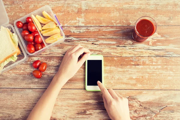 Zamknij się rąk z smartphone jedzenie na stole — Zdjęcie stockowe
