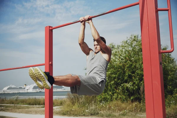 Jongeman die buiten op de horizontale balk traint — Stockfoto
