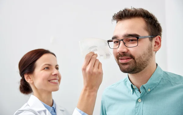 Optometrista com régua e paciente na clínica ocular — Fotografia de Stock