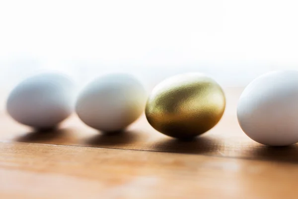 Perto de ovos de páscoa dourados e brancos em madeira — Fotografia de Stock